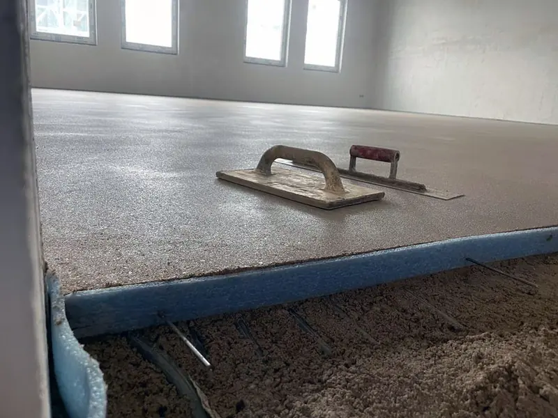 Frisch abgezogener Estrich mit Glättkelle und blauem Randdämmstreifen