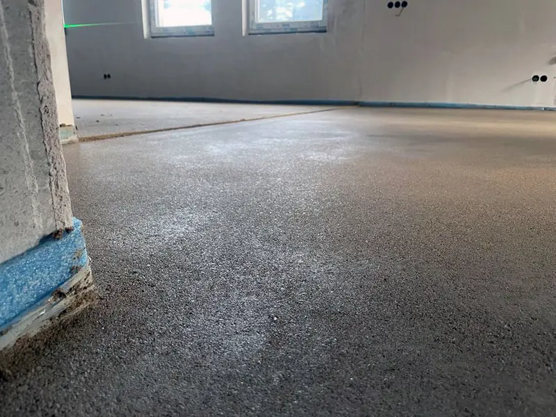 Eingebrachter Heizestrich im Rohbau neben einem Randdämmstreifen
