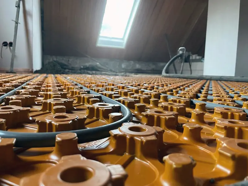 Orange Noppenplatte mit verlegten Heizrohren unter einer Dachschräge